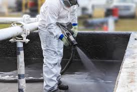 Worker applying polyurea coating spray