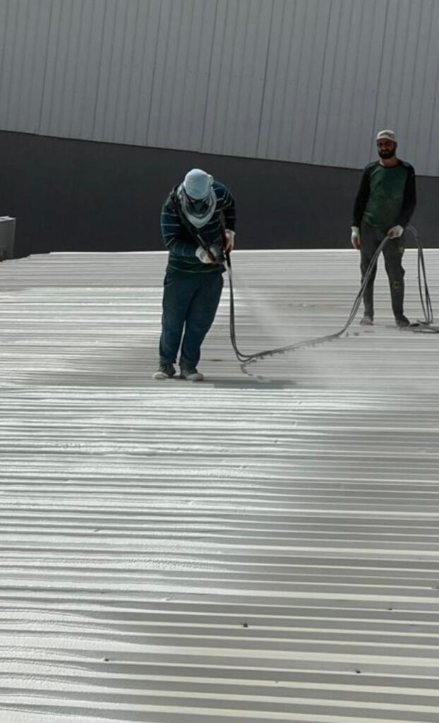 "A man applying spray on the roof"